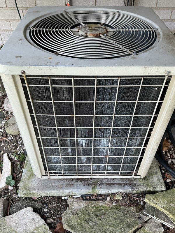 Completed comprehensive Gold AC inspection and maintenance on outdoor condensing unit showing signs of age and weathering. Performed standard tune-up procedures including inspection of condenser coils, fan assembly, and refrigerant lines. Successfully installed customer-provided thermostat in living room to replace existing unit. Condenser unit exhibited dirt accumulation on exterior surfaces and protective grilles, with minor surface deterioration and algae growth on concrete pad. All electrical connections, refrigerant lines, and mounting hardware inspected and found secure. Fan guard and blade assembly operational. System tested and confirmed functioning properly following maintenance and thermostat installation.