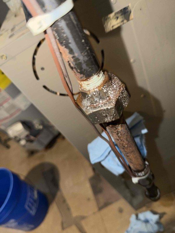 Responded to customer report of gas odor during furnace burner ignition. Upon inspection, found flame-sensitive insulation blanket improperly positioned near burner assembly, creating potential combustion concern. Identified corroded gas line connection with visible deterioration and mineral deposits on threaded fitting, which was determined to be the source of gas smell during startup. Repositioned insulation blanket to manufacturer specifications and secured with appropriate fasteners. Recommended immediate gas line repair or replacement due to advanced corrosion on connection fitting to prevent future gas leaks. Unit currently operational and heating properly, but customer advised of safety concern requiring follow-up service for corroded gas piping.