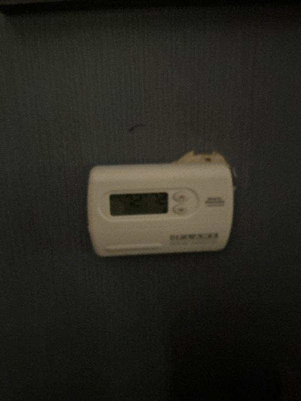 Responded to service call for Honeywell digital thermostat not responding to temperature setting adjustments on 2-week-old equipment located on main floor. Performed diagnostic inspection, removed thermostat cover to examine internal circuit board, wiring connections, and LCD display components. Verified proper power supply connections via red and black wiring, inspected green circuit board for defects, and tested thermostat functionality to identify and resolve temperature control issue.