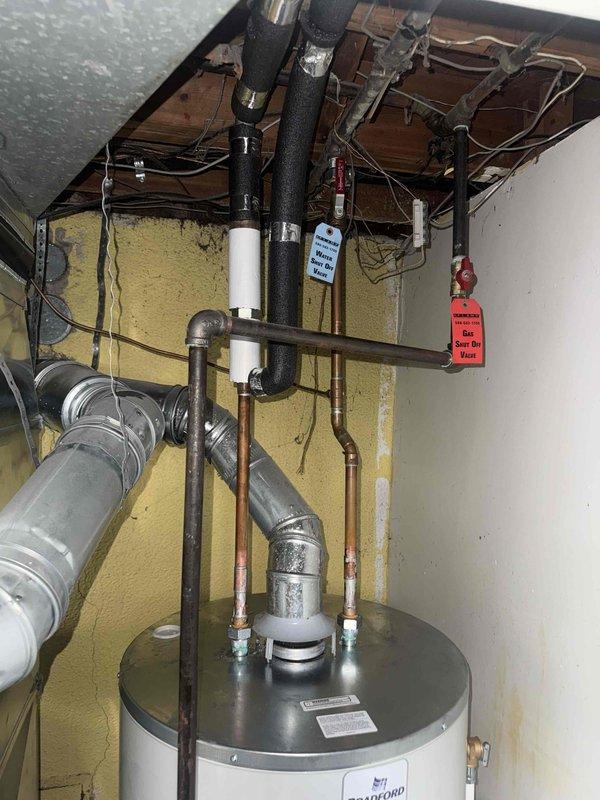 Completed mechanical-only installation of a 50-gallon short Bradford White tanked water heater in utility room. Reconnected all water supply lines using copper piping with proper fittings, installed black insulated hot water distribution lines, and configured cold water inlet connections. Secured all piping runs with appropriate straps and hangers, ensured proper clearances per manufacturer specifications, and verified all connections for leak-free operation. Unit was positioned on existing floor surface with adequate ventilation access and proper venting configuration maintained through existing ductwork system.