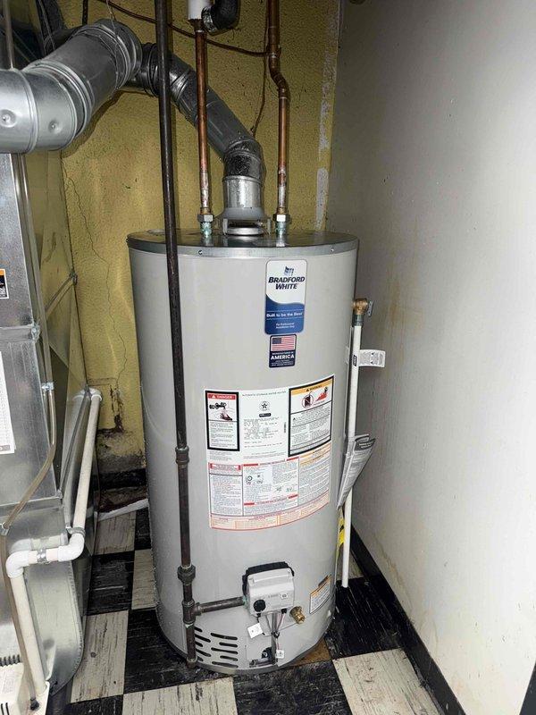 Completed mechanical-only installation of a 50-gallon short Bradford White tanked water heater in utility room. Reconnected all water supply lines using copper piping with proper fittings, installed black insulated hot water distribution lines, and configured cold water inlet connections. Secured all piping runs with appropriate straps and hangers, ensured proper clearances per manufacturer specifications, and verified all connections for leak-free operation. Unit was positioned on existing floor surface with adequate ventilation access and proper venting configuration maintained through existing ductwork system.