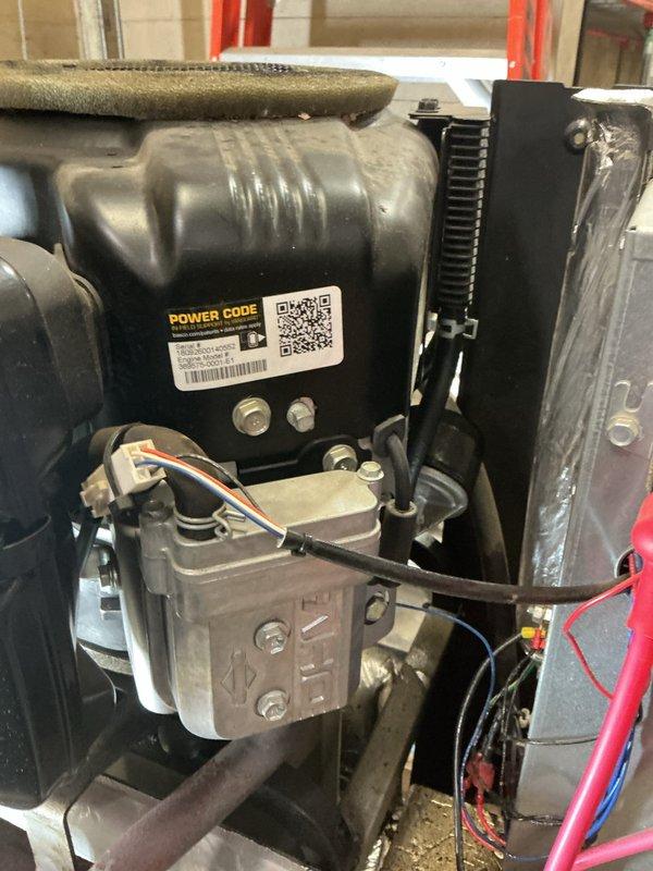 # Generator Repair

Responded to service call for generator system requiring repair. Upon inspection, identified issues with the engine assembly and associated components requiring attention. Performed comprehensive diagnostic assessment of the POWER CODE branded engine unit, examining electrical connections, fuel system components, and cooling system integrity.

Addressed mechanical issues within the engine assembly, including inspection and service of the carburetor/fuel delivery system visible in the lower portion of the unit. Verified proper operation of air-cooled engine components, ensuring adequate heat dissipation through the finned housing design. Examined and tested all electrical wiring connections, including orange and red insulated wires connected to various engine points, confirming proper voltage and continuity throughout the system.

Inspected and serviced HVAC/refrigeration components integrated with the generator system, including the black metallic compressor housing