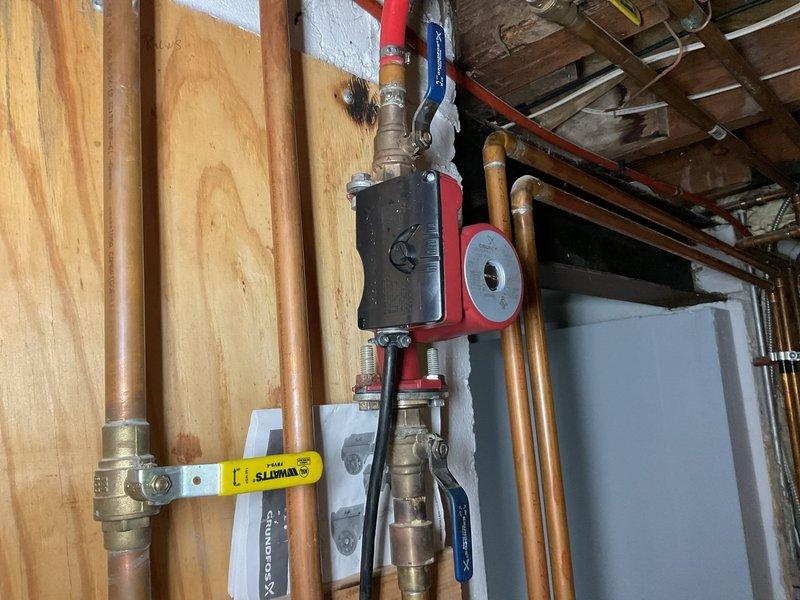 Completed sump pump system replacement and installation of i-Link SP-B4 Four Zone Pump Controller with integrated Grundfos circulator pump. The new controller was mounted to the wall with proper electrical connections made to terminal blocks, featuring multi-zone monitoring capabilities with illuminated power and zone indicator lights. Installed red-housed Grundfos circulator pump on copper piping network with electrical junction box, incorporating brass ball valves and various diameter copper pipe connections for optimal water circulation. All conduits were properly secured with metal clamps and cable ties, and system was tested to verify proper operation across all zones.