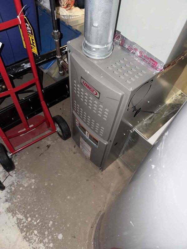 Responded to service call for furnace repair estimate on 6-year-old Lennox unit located in basement. Upon arrival, confirmed unit was operational and providing heat. Performed comprehensive visual inspection of furnace cabinet, ductwork connections, and surrounding installation area. Documented existing conditions with photographs showing main supply duct transition at floor level and overall furnace installation with vertical supply plenum. Noted typical dust accumulation on ductwork surfaces consistent with system age. Verified furnace accessibility and clearances meet code requirements. Unit remains functional at time of inspection. Provided customer with assessment findings and repair estimate for consideration.