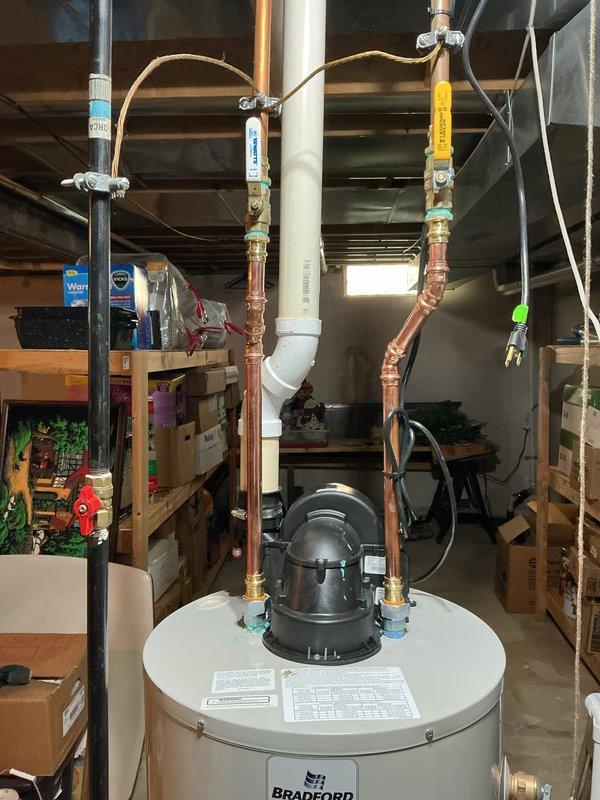 Completed installation and reconnection of a 40-gallon Bradford White power vent water heater in basement utility area. Installed copper supply piping with brass fittings and isolation valves, connected power vent exhaust system, and verified all connections for proper operation. Unit tested and operational upon completion.