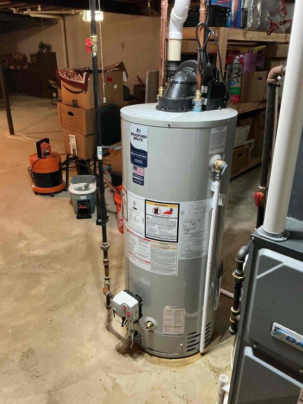 Completed installation and reconnection of a 40-gallon Bradford White power vent water heater in basement utility area. Installed copper supply piping with brass fittings and isolation valves, connected power vent exhaust system, and verified all connections for proper operation. Unit tested and operational upon completion.