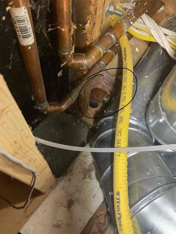 Responded to gas leak emergency in residential service line following utility company shutoff. Conducted comprehensive pressure test on gas piping system throughout crawl space and utility areas. Located leak in service line connection point where yellow CSST flexible gas line interfaces with copper piping near floor joists. Inspected all gas line connections, fittings, and joints using soap solution and pressure gauge to verify leak location and ensure no additional compromise points existed in the system. Documented existing infrastructure including aged copper piping with multiple elbow joints, flexible gas line rated for 5 PSI, and surrounding HVAC ductwork. Identified moisture damage on concrete floor surface and weathered wooden framing that required monitoring. Photographed leak location, connection points, and overall gas line routing for repair documentation. System remains inoperable until leak repair is completed and utility company restores gas service following re-inspecti
