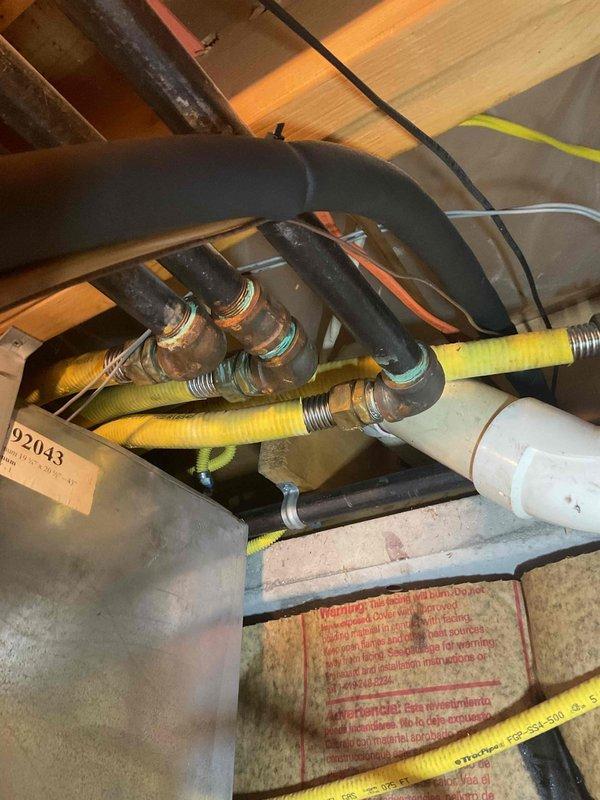 Responded to gas leak emergency in residential service line following utility company shutoff. Conducted comprehensive pressure test on gas piping system throughout crawl space and utility areas. Located leak in service line connection point where yellow CSST flexible gas line interfaces with copper piping near floor joists. Inspected all gas line connections, fittings, and joints using soap solution and pressure gauge to verify leak location and ensure no additional compromise points existed in the system. Documented existing infrastructure including aged copper piping with multiple elbow joints, flexible gas line rated for 5 PSI, and surrounding HVAC ductwork. Identified moisture damage on concrete floor surface and weathered wooden framing that required monitoring. Photographed leak location, connection points, and overall gas line routing for repair documentation. System remains inoperable until leak repair is completed and utility company restores gas service following re-inspecti