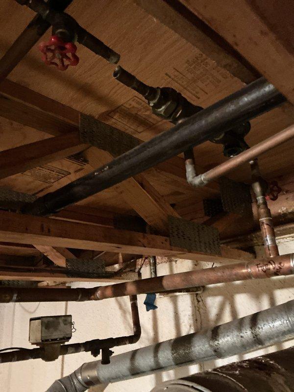 Performed diagnostic evaluation on basement-located furnace to assess equipment condition and determine repair versus replacement recommendations. Conducted thorough inspection of heating system, including visual assessment of furnace components, ductwork connections, and associated plumbing infrastructure in basement ceiling area. Documented equipment condition through photographic evidence showing exposed joists, utility piping, and structural elements surrounding the HVAC installation for comprehensive evaluation and estimate preparation.