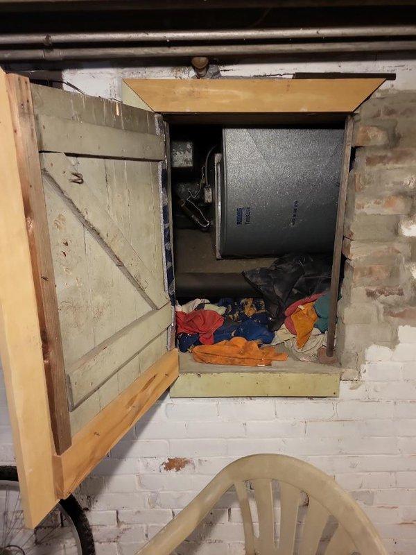 Completed estimate for replacement of 30-year-old furnace unit located in crawl space accessed through interior wooden panel. Assessed existing HVAC equipment and ductwork configuration in confined below-grade area with exposed dirt flooring, evaluated current system connections including flexible metallic conduit and plenum assembly, and documented conditions for furnace replacement proposal.