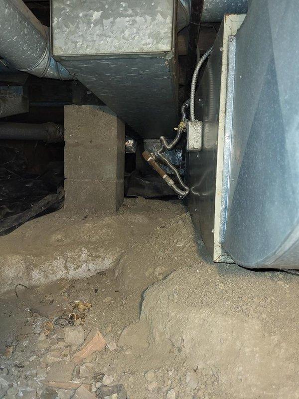 Completed estimate for replacement of 30-year-old furnace unit located in crawl space accessed through interior wooden panel. Assessed existing HVAC equipment and ductwork configuration in confined below-grade area with exposed dirt flooring, evaluated current system connections including flexible metallic conduit and plenum assembly, and documented conditions for furnace replacement proposal.