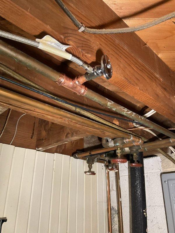 Replaced faulty icemaker supply valve and connecting hose assembly to restore water supply to refrigerator ice maker. Accessed plumbing connections in basement ceiling space, removed old valve and deteriorated supply line, installed new chrome shut-off valve with braided stainless steel flex line, and verified proper water flow and leak-free connections upon completion.