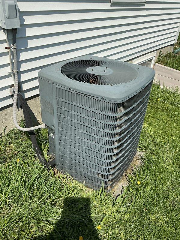 Completed comprehensive Gold AC inspection on single residential air conditioning system with equipment under 10 years old and air handler located in basement. Performed thorough examination of outdoor condenser unit, which showed normal operational wear with dust and dirt accumulation on metal fins and housing. Verified unit functionality and proper operation of all components including condenser coils, fan assembly, and electrical connections. Inspected refrigerant lines, electrical disconnect box, and PVC conduit for proper installation and condition. Confirmed condenser unit remains level on concrete pad with adequate clearance, though noted some grass growth and minor debris accumulation around base of unit and pad perimeter. System operating within normal parameters at time of inspection.