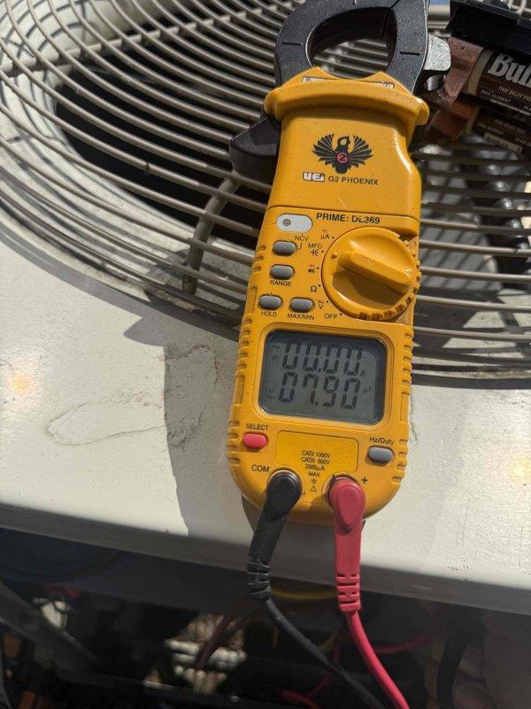 Completed comprehensive Gold AC inspection on single residential unit over 10 years old with air handler located in basement. Performed thorough evaluation of outdoor condenser unit, which showed good overall condition with clean vertical fins and minimal debris accumulation. Conducted electrical measurements using digital clamp meter to verify proper amperage draw and system performance. Unit was operational at time of inspection with no immediate issues identified. Documented equipment condition through photographic records showing condenser placement, clearances, and electrical disconnect box positioning.
