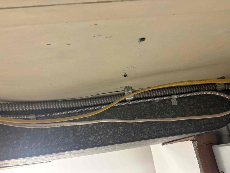 Performed electrical inspection of light fixture wiring throughout home with older electrical system. Evaluated electrical panel and circuit breaker configuration, documented existing wiring conditions including flexible metal conduit and cable routing in ceiling/attic spaces. Assessed fixture wiring compatibility and identified circuits requiring attention for safe operation of lighting fixtures.