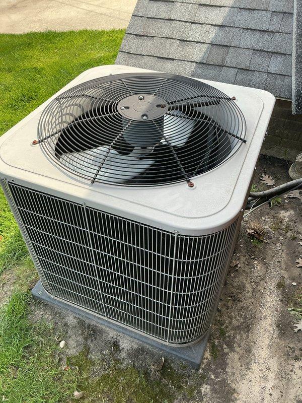 Completed comprehensive Gold AC inspection on single residential cooling system with air handler located on lower level. Performed thorough evaluation of outdoor condenser unit, which was found to be in functional condition with proper placement on concrete pad and adequate clearance from surrounding area. Inspected all exterior components including fan assembly, protective grilles, metal housing with vertical louvers, and refrigerant lines, confirming system operational status and documenting equipment condition through photographic records.