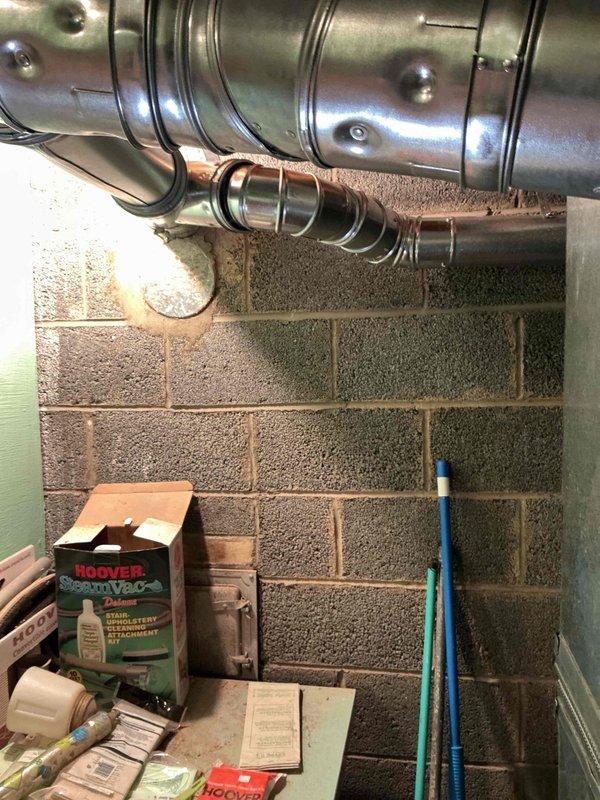 Responded to municipal inspection follow-up for recently completed HVAC installation. Inspector identified water heater venting with severe back pitch creating potential carbon monoxide hazard. Documented existing vent configuration with photographs showing horizontal ductwork runs and flexible connector sections in basement mechanical area. Venting requires correction to establish proper upward slope and ensure safe exhaust of combustion gases. Coordinated with management to schedule corrective work and eliminate CO risk.