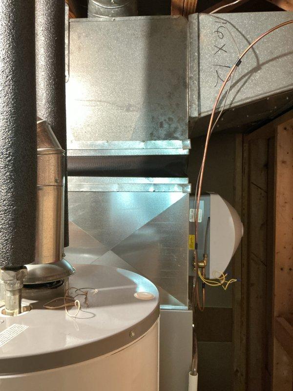 Conducted comprehensive evaluation of 10-15 year old HVAC system including air conditioning unit, furnace, and water heater located in basement. Assessed air conditioning unit with history of low refrigerant requiring recharge approximately five years prior, and inspected deteriorating black rubber insulation covering on refrigerant line set connecting outdoor condenser to indoor air handler. Provided replacement options for air conditioning unit only versus complete HVAC system replacement including both air conditioner and furnace, and evaluated water heater condition as part of overall mechanical system assessment.