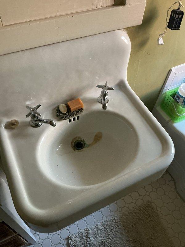Replaced faucet assembly on vintage pedestal sink with chrome cross-handle fixtures and center spout. Verified proper water flow and tested for leaks to ensure complete installation and functionality.