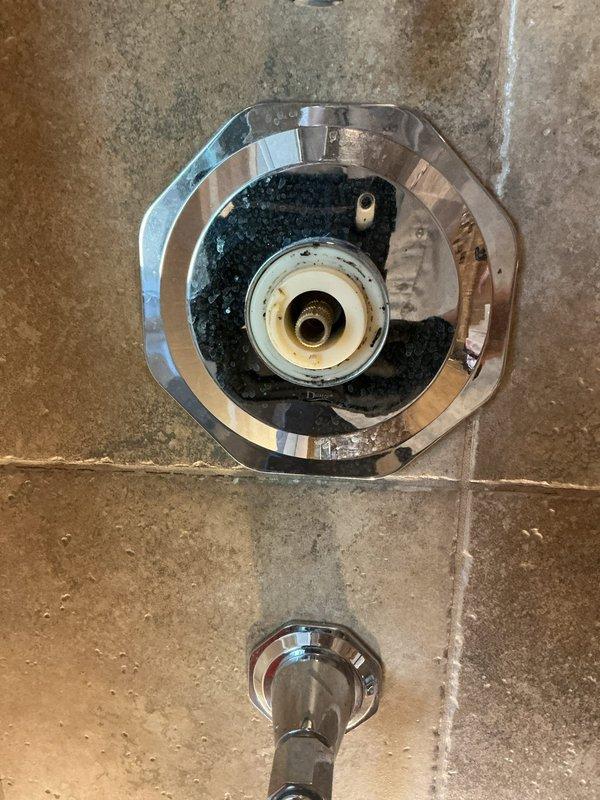 Responded to service call for whining/screaming noise occurring during shower operation. Upon inspection, identified worn shower valve cartridge as the source of the noise complaint. Removed octagonal chrome escutcheon plate and extracted deteriorated cartridge showing age-related discoloration and compromised sealing components. Installed new replacement cartridge with fresh rubber gaskets and seals. Tested all three fixtures in the vertical column configuration—diverter valve, temperature control valve, and volume control valve—to ensure proper operation and verify elimination of noise issue. System now operates quietly with normal water flow and pressure.