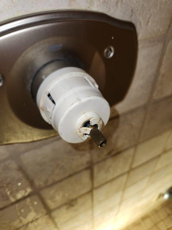 Responded to service call for no hot water to shower, toilet issue, and basement leak. Upon inspection, identified failed shower valve cartridge with significant wear, discoloration, and mineral buildup on the valve stem assembly. The cartridge showed brownish residue and deterioration at the base, preventing proper hot water flow control. Additionally, discovered damaged tile work surrounding the shower valve with broken sections exposing substrate, water staining, and mineral deposits indicating previous leak activity. Removed worn cartridge assembly from brushed metal escutcheon plate and replaced with new valve cartridge to restore hot water function. Addressed underlying plumbing concerns contributing to basement leak by repairing compromised valve connections. Recommend future tile repair around fixture to prevent moisture intrusion and further wall damage.