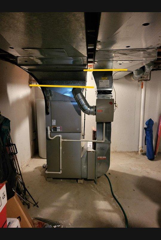 Conducted furnace replacement estimate for 10+ year old unit with identified cracked heat exchanger in second cell. Inspected basement-mounted HVAC system including furnace, ductwork, and associated equipment. Documented existing equipment configuration with gray furnace unit, metallic supply ductwork with yellow support straps, black flexible connections, and white PVC condensate piping. Assessed mechanical room layout and equipment accessibility for replacement planning. Verified system operation and provided recommendations for furnace replacement due to heat exchanger failure, which poses safety concerns and cannot be repaired.