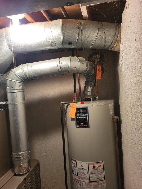 Conducted furnace replacement estimate for 10+ year old unit with identified cracked heat exchanger in second cell. Inspected basement-mounted HVAC system including furnace, ductwork, and associated equipment. Documented existing equipment configuration with gray furnace unit, metallic supply ductwork with yellow support straps, black flexible connections, and white PVC condensate piping. Assessed mechanical room layout and equipment accessibility for replacement planning. Verified system operation and provided recommendations for furnace replacement due to heat exchanger failure, which poses safety concerns and cannot be repaired.