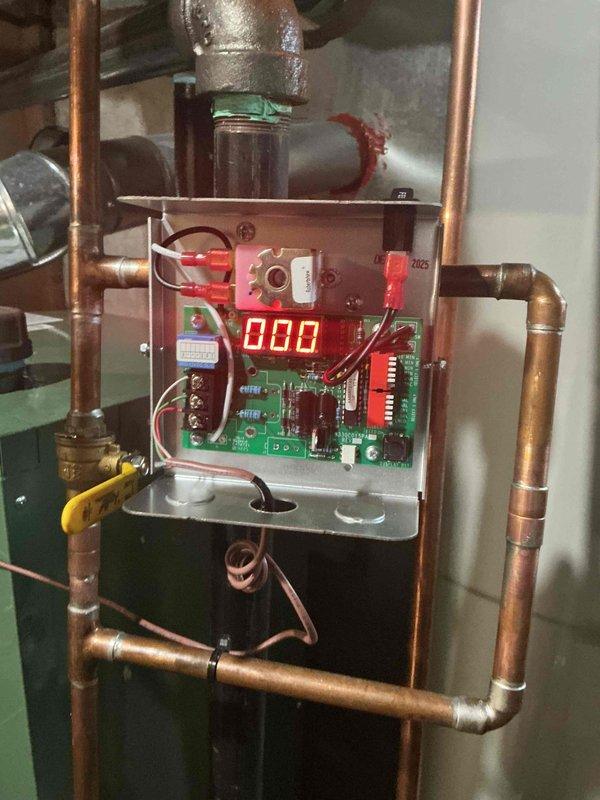 Responded to callback for boiler system with reported black water accumulation in furnace tube. Upon inspection, verified hydronic heating system remained operational with proper heat output. Examined boiler control panel, copper piping network, and associated plumbing connections throughout the mechanical system. Documented existing conditions of green boiler unit, control circuitry displaying normal readings, and copper pipe configuration with expansion tank. System assessed and photographed for service records, with no immediate safety concerns identified during visit.