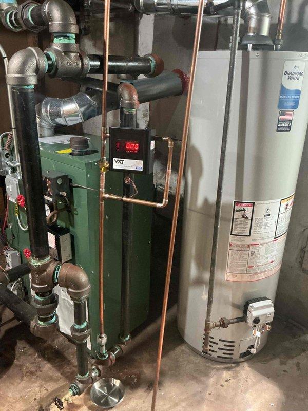 Responded to callback for boiler system with reported black water accumulation in furnace tube. Upon inspection, verified hydronic heating system remained operational with proper heat output. Examined boiler control panel, copper piping network, and associated plumbing connections throughout the mechanical system. Documented existing conditions of green boiler unit, control circuitry displaying normal readings, and copper pipe configuration with expansion tank. System assessed and photographed for service records, with no immediate safety concerns identified during visit.