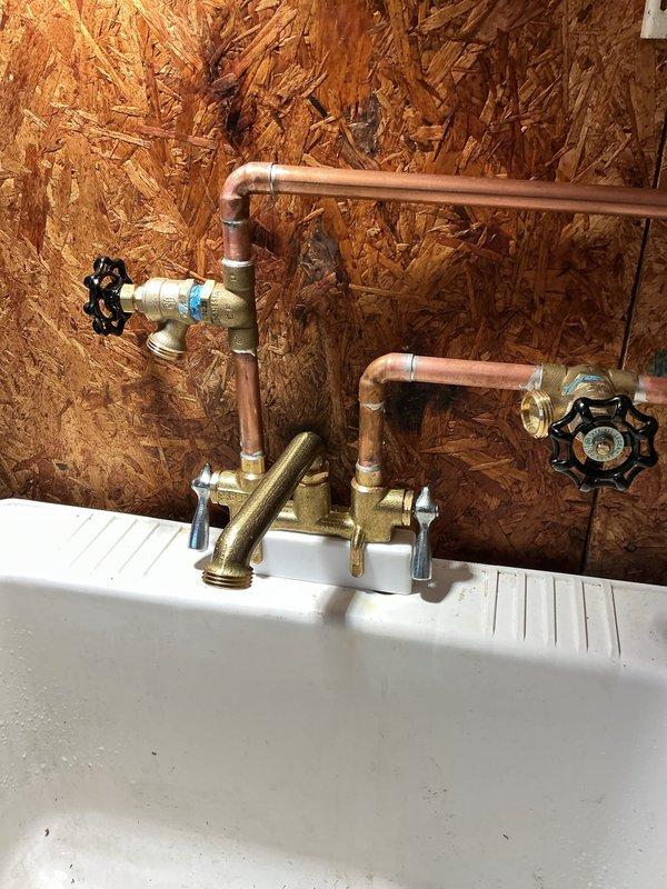 Returned to complete plumbing work following city water service restoration. Successfully completed majority of scheduled repairs with exception of #1 valve replacement, which requires city water shutoff to proceed safely. Installed copper supply lines and laundry tub rough-in above meter location, pending final connections once valve replacement is completed. Pressurized system and conducted comprehensive leak testing throughout home with satisfactory results. Identified debris accumulation in lavatory and kitchen faucets due to old galvanized piping system; both fixtures will require replacement on subsequent visit. Documented water-damaged floor joists in crawl space area near plumbing infrastructure and newly installed utility sink with dual shutoff valves mounted to OSB backing. All accessible plumbing connections functioning properly at time of departure. Advised property owner to schedule follow-up appointment once municipal water shutoff is coordinated for valve installation an