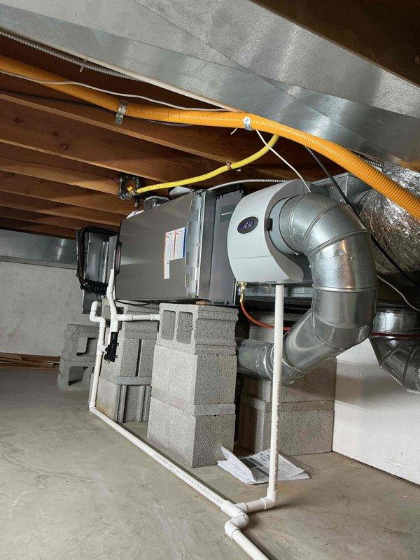 Completed full HVAC system installation including a 45,000 BTU horizontal furnace and 2-ton air conditioning unit in rear configuration. Installed humidifier, reconnected existing components, and routed all necessary ductwork, PVC condensate drainage, and electrical conduit. Unit mounted on concrete block supports in basement mechanical space with proper venting and gas connections. Mechanical permit obtained and system tested for proper operation upon completion.