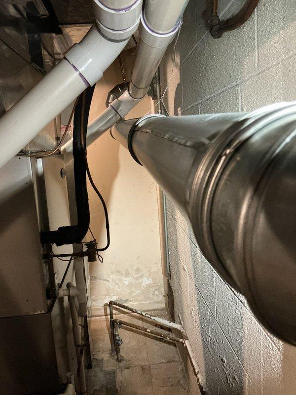 Corrected a code violation where the water heater B-vent was in direct contact with the furnace PVC vent pipe. Repositioned and secured the B-vent to maintain the required 1-inch clearance from combustible materials and adjacent piping, bringing the installation into compliance with safety standards.
