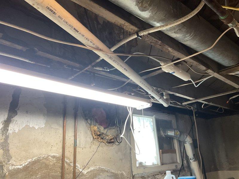 Conducted comprehensive assessment of existing cast iron plumbing stack system for replacement estimate. Inspection revealed extensive corrosion and deterioration of cast iron piping throughout the basement utility area, particularly affecting horizontal runs and vertical stack connections near the water heater. Documented severely rusted pipe sections showing advanced oxidation and structural compromise. Evaluated existing drainage system configuration including overhead piping layout, exposed joists, and connection points to current plumbing infrastructure. Photographed corroded cast iron components, water heater connections, and basement utility space conditions to provide detailed visual documentation for estimate preparation. Provided recommendations for complete cast iron stack replacement with modern piping materials.