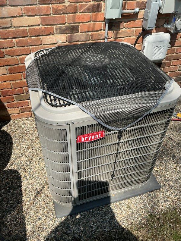 Completed comprehensive Gold AC inspection on 2018 Bryant air conditioning system with air handler located in garage. Performed full system evaluation of outdoor condensing unit, verified proper operation of all components, inspected electrical connections, checked refrigerant levels, examined condenser coil condition, and confirmed adequate airflow through unit. Unit found to be in good operating condition with protective mesh guard in place and proper clearance maintained around equipment on gravel pad.