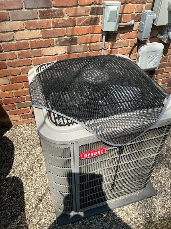 Completed comprehensive Gold AC inspection on 2018 Bryant air conditioning system with air handler located in garage. Performed full system evaluation of outdoor condensing unit, verified proper operation of all components, inspected electrical connections, checked refrigerant levels, examined condenser coil condition, and confirmed adequate airflow through unit. Unit found to be in good operating condition with protective mesh guard in place and proper clearance maintained around equipment on gravel pad.