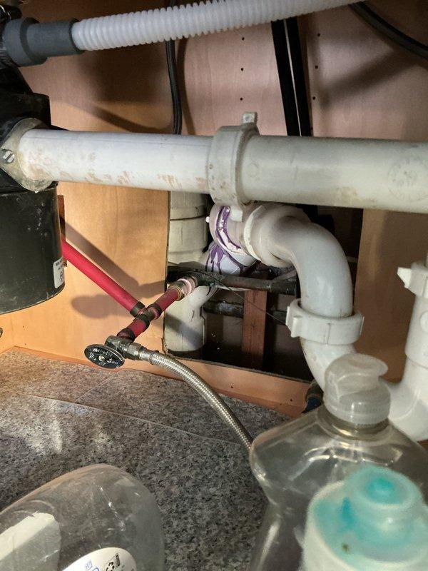 Installed condensate drain line for HVAC system in attic space following indoor comfort equipment installation. Routed PVC piping through attic framework to connect to existing plumbing infrastructure beneath kitchen sink, ensuring proper drainage and code compliance for new air conditioning unit.