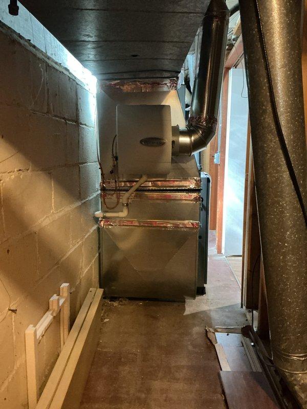 Completed full HVAC system replacement including installation of 70,000 BTU furnace and 2.5 ton rear-discharge air conditioning unit in basement mechanical room. Relocated furnace 3 inches to right to accommodate 1-inch filter access, connected all ductwork to existing distribution system, and installed S40 thermostat for system control. Performed refrigerant line flush, installed condensate pump for proper drainage, and reconnected existing humidifier to new furnace. Positioned outdoor condenser unit on gravel pad with proper clearances, installed electrical disconnect, and completed all electrical connections per code requirements. Secured mechanical and electrical permits prior to installation. Remeasured system specifications and registered AHRI certificate number 215663885 for utility rebate qualification. Tested all system operations including heating, cooling, humidification, and thermostat functionality to verify proper performance and customer satisfaction.