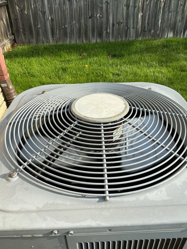 Completed comprehensive Gold AC inspection on residential cooling system. Unit confirmed operational at time of service. Performed thorough evaluation of outdoor condenser unit, including visual inspection of fan assembly, housing condition, and proper placement on concrete pad. Inspected electrical disconnect box mounted on exterior wall, verified accessibility and condition of disconnect mechanism and fuse holder. Air handler and evaporator coil located in basement area. Documented equipment condition through photographic records showing exterior disconnect components with visible specification plate and outdoor condenser unit positioned in backyard setting. Provided estimate for thermostat replacement as requested. System operating normally with no immediate service concerns identified during inspection.