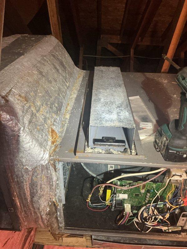 Responded to no cooling complaint on 12-year-old air conditioning system located in attic. Upon arrival, found unit completely inoperative with air handler panel open exposing control board and internal wiring. Performed diagnostic evaluation of electrical components, capacitor, and blower motor assembly. Inspected control board connections, examining red, yellow, white, and black wire terminations for loose connections or damage. Evaluated cylindrical blower motor showing signs of age-related wear and dust accumulation on housing and surrounding ductwork. Assessed condition of metallic flexible ductwork exhibiting yellowing and material deterioration consistent with system age. Documented equipment condition through photographs showing exposed circuit board, wiring harnesses, and mechanical components for service records. System required comprehensive troubleshooting to identify root cause of complete system failure and restore cooling operation.