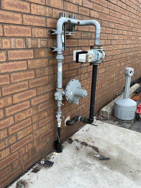 Responded to commercial property for gas pressure test following city-identified gas leak at exterior meter assembly. Performed comprehensive pressure test on gas piping system from exterior meter location through interior distribution lines. Inspected exterior gas meter installation, regulator assembly, and associated piping mounted on building exterior, noting staining at concrete pad base. Evaluated interior gas piping system including vertical runs and horizontal distribution lines throughout facility. Completed pressure test protocol to verify system integrity and identify any leak points in accordance with municipal requirements for gas service restoration.