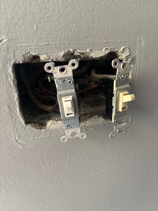 Responded to service call for non-functioning outdoor flood lights on two-story brick residence. Upon inspection, accessed exterior lighting circuit and identified failed switching mechanism controlling the flood light fixtures. Removed defective dual-gang switch assembly from interior wall cavity, verified wiring connections, and prepared for replacement of switching components to restore proper operation of exterior lighting system.