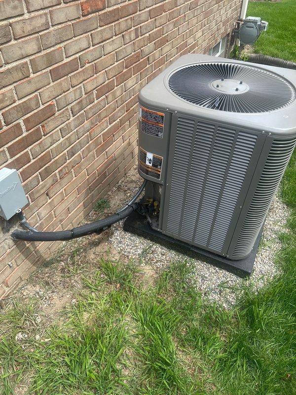 Completed AC system start-up on residential split system with basement evaporator coil and outdoor condensing unit. Verified proper refrigerant charge using digital scale, confirmed unit operational parameters, and documented equipment installation with condenser positioned on gravel pad with proper clearances and electrical disconnect in place.