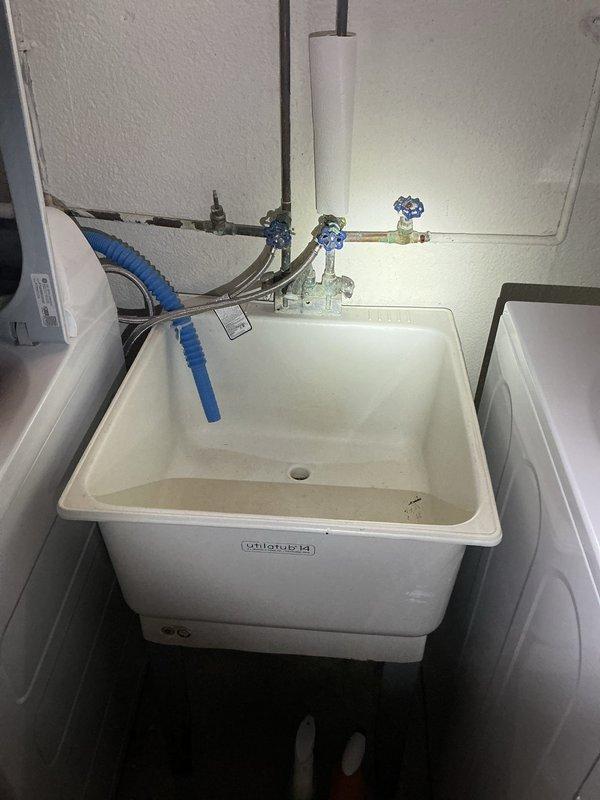Conducted comprehensive plumbing assessment for basement utility area to provide estimates on multiple fixture and system improvements. Evaluated existing laundry tub installation and assessed condition of faucet and shut-off valves for potential replacement. Inspected sump pump system configuration, identifying dual primary pump setup without battery backup or alarm system, and evaluated options for adding high-water alarm and backup pump installation to prevent flooding risk. Examined sump crock for lid installation options to reduce moisture migration and odor control in utility space. Investigated cast iron drain connection at concrete floor level, determining visible deterioration was concrete splatter from previous drain work rather than pipe degradation, and recommended protective coating application to prevent further flaking. Documented all fixtures and conditions with photographs for estimate preparation.