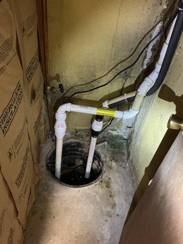 Conducted comprehensive plumbing assessment for basement utility area to provide estimates on multiple fixture and system improvements. Evaluated existing laundry tub installation and assessed condition of faucet and shut-off valves for potential replacement. Inspected sump pump system configuration, identifying dual primary pump setup without battery backup or alarm system, and evaluated options for adding high-water alarm and backup pump installation to prevent flooding risk. Examined sump crock for lid installation options to reduce moisture migration and odor control in utility space. Investigated cast iron drain connection at concrete floor level, determining visible deterioration was concrete splatter from previous drain work rather than pipe degradation, and recommended protective coating application to prevent further flaking. Documented all fixtures and conditions with photographs for estimate preparation.