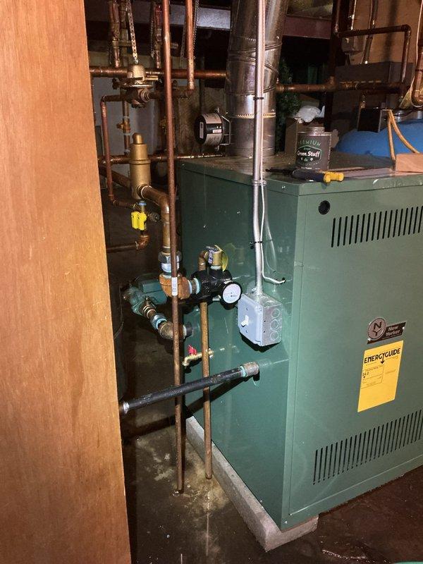 # HVAC Service - Water Leak

Responded to service call for reported water leak on residential boiler system located in basement. Upon arrival, performed comprehensive diagnostic inspection of green-painted boiler unit and associated hydronic heating system components. 

Conducted thorough visual examination of all copper piping connections, circulator pumps, pressure relief valve, expansion tank connections, and zone valves to identify source of water leak. Inspected pressure gauge readings and assessed system pressure. Examined all threaded connections, compression fittings, and solder joints throughout the piping network for signs of active leaking or moisture accumulation.

Checked expansion tank for proper air charge and inspected tank connection point for potential leak source. Evaluated condition of pressure relief valve discharge pipe and tested valve operation. Inspected all visible gaskets, seals, and union connections on boiler cabinet and associated piping.

Documented equip