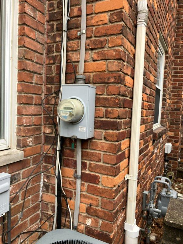 Provided estimate for complete HVAC system replacement of non-functional 10+ year old air conditioning unit located in attic. Due to extremely narrow stairway access, specified SlimTech equipment required for installation. Documented existing outdoor condenser unit, electrical service connections, and utility infrastructure mounted on exterior brick wall to ensure proper replacement specifications and equipment compatibility.