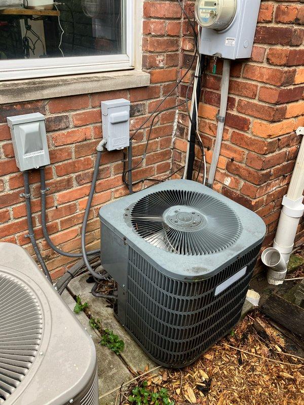 Provided estimate for complete HVAC system replacement of non-functional 10+ year old air conditioning unit located in attic. Due to extremely narrow stairway access, specified SlimTech equipment required for installation. Documented existing outdoor condenser unit, electrical service connections, and utility infrastructure mounted on exterior brick wall to ensure proper replacement specifications and equipment compatibility.