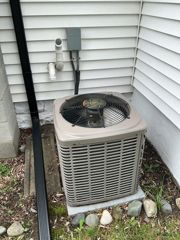 Completed comprehensive Gold AC inspection on 15-year-old residential cooling system with air handler located in basement. Performed electrical diagnostics using digital multimeter to test capacitor and measure voltage readings at outdoor condenser unit, verifying proper electrical operation of all components. Inspected outdoor condenser unit positioned on concrete pad against home exterior, checked fan assembly and grille protection, evaluated surrounding area for proper clearance and debris removal, and documented system condition through photographic records for maintenance history.