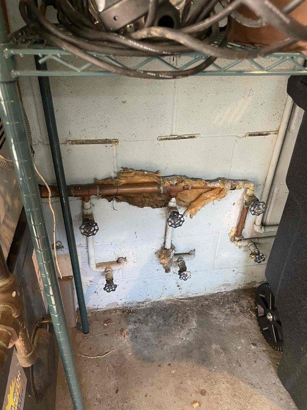 Conducted site assessment for new boiler installation to replace 30-year-old unit located in garage mechanical space. Documented existing system configuration including aged boiler with extensive copper piping, multiple zone valves, expansion tank, and manifold connections. Noted significant water damage and deterioration on interior cabinet wall surfaces, corroded substrate material, and general wear throughout mechanical space indicating end-of-life system conditions requiring complete replacement.