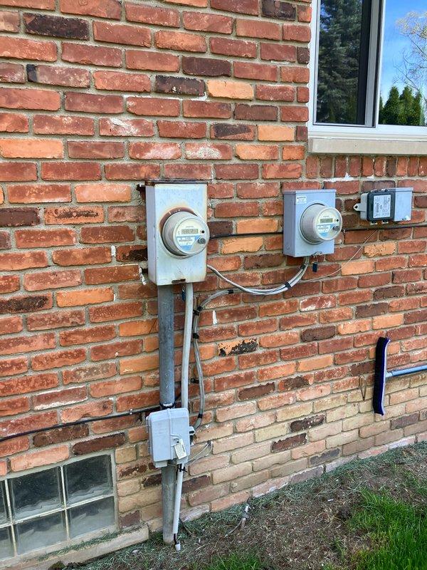 Completed comprehensive HVAC system evaluation for replacement estimate on a 2007 residential air conditioning system presenting with critically low refrigerant levels. Inspected outdoor condenser unit installed on exterior brick wall foundation and assessed basement-located air handler and evaporator coil assembly. Documented existing system age at seventeen years with noted refrigerant loss indicating potential coil leaks or compressor seal failure requiring full system replacement rather than repair. Verified furnace heat exchanger was previously replaced in 2020 and remains safe for continued operation, allowing for air conditioning replacement while retaining existing heating equipment if desired. Photographed current equipment installation including condenser placement, electrical service connections with dual meter configuration, and overall system accessibility for replacement work. Provided technical findings and replacement options to homeowner for equipment upgrade decision.
